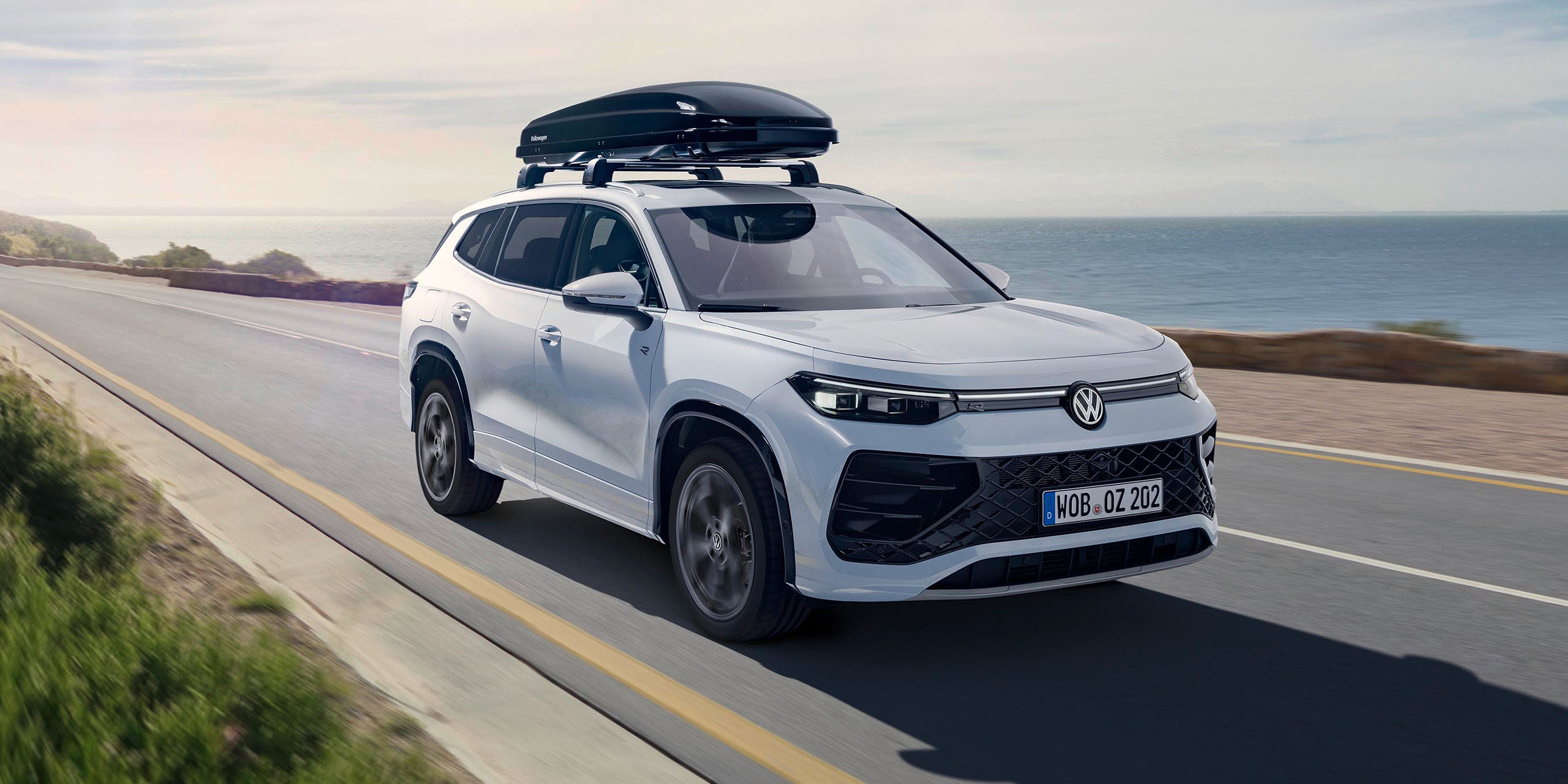 Bílý vůz Volkswagen se střešním boxem