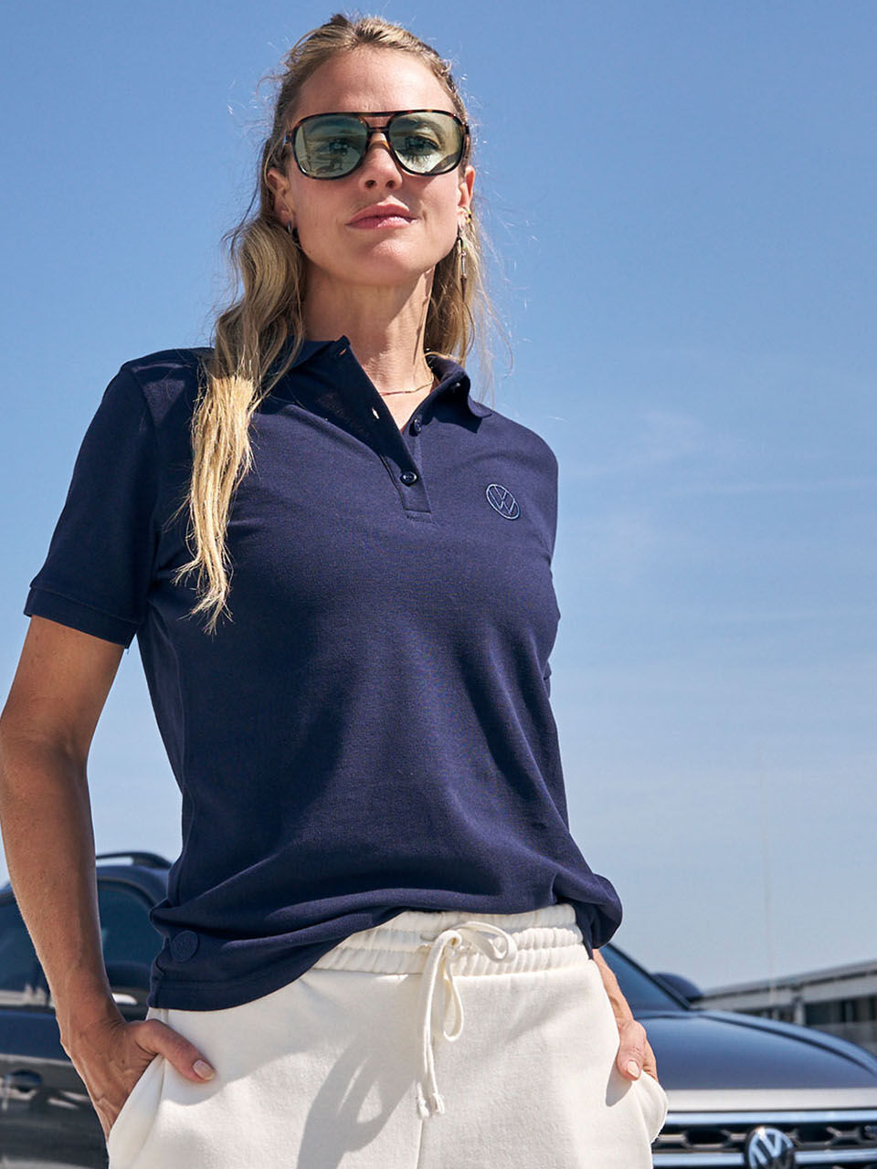 Žena v modrém tričku Volkswagen a vozem Volkswagen za ní