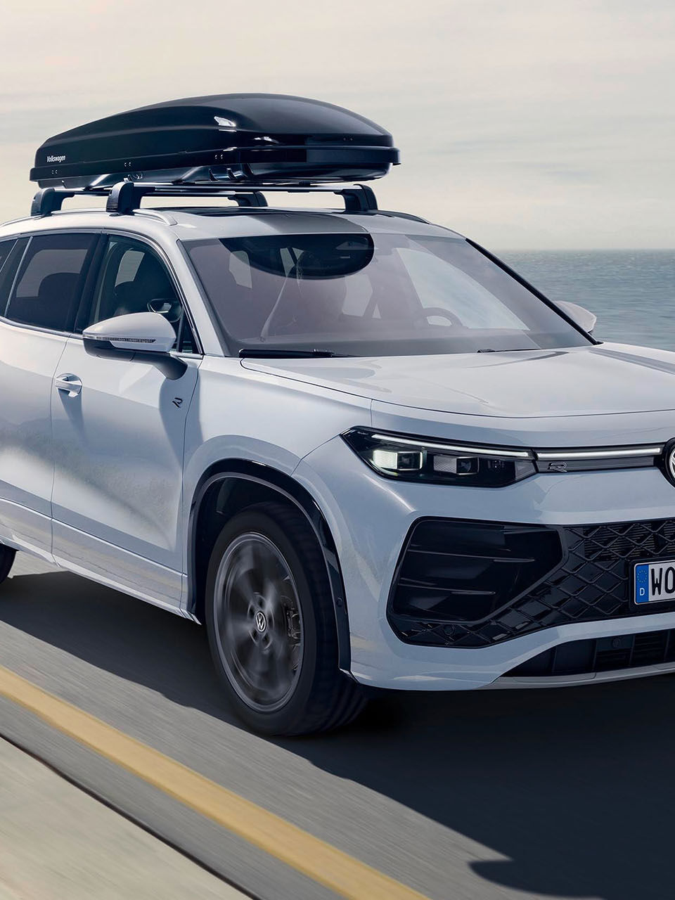 Bílý vůz Volkswagen se střešním boxem