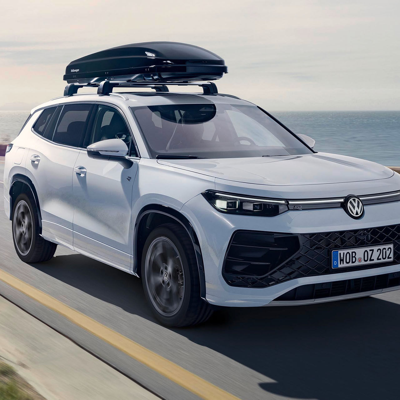 Bílý vůz Volkswagen se střešním boxem